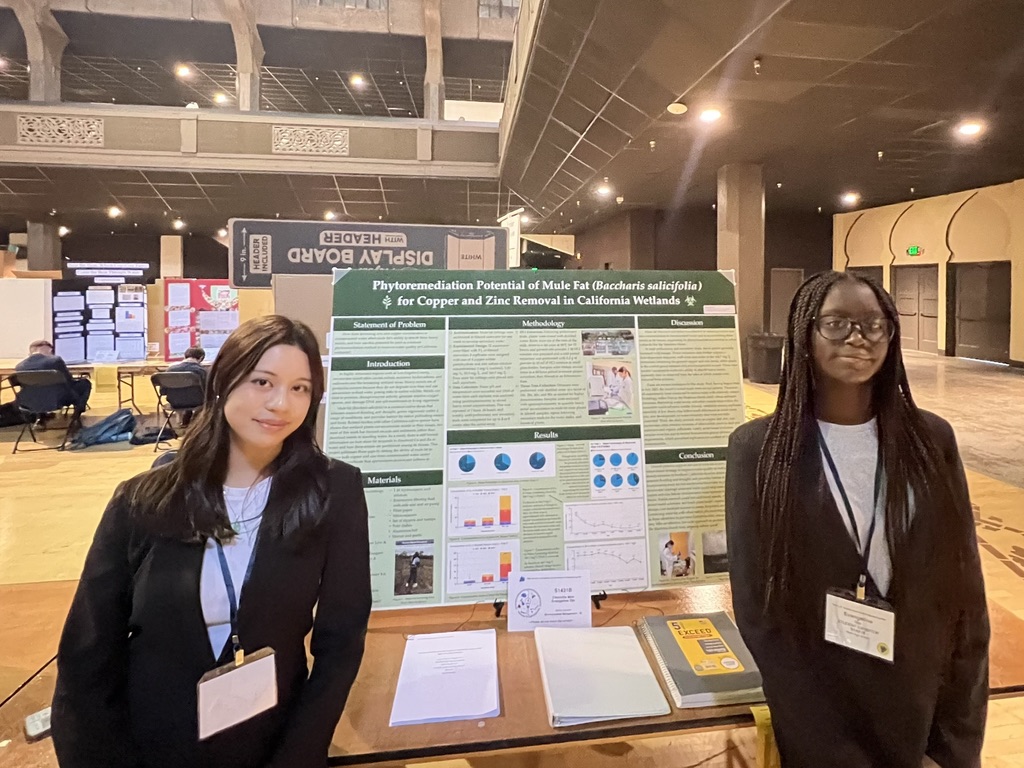 Charlotte Moo and Evangeline Ojo stand next to their research table at the LA County Science Fair 2026